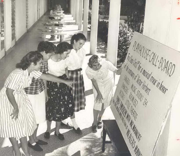 Students reading a call board announcing an audition for the musical, Sweet Mystery
